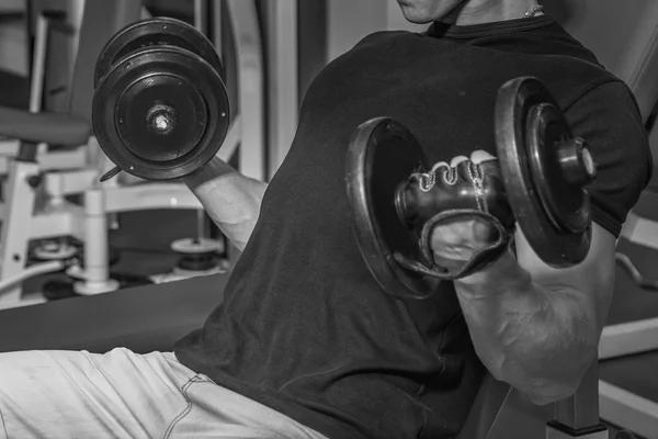 健美运动员使得用哑铃在健身房锻炼。手上的工作告诉肌肉。用尽最后的锻炼。体育杂志和网站的照片. — 图库照片