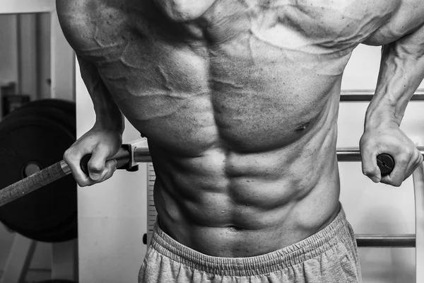 Gespierde man met gewichten in de sportschool uit te werken. Man maakt oefeningen. — Stockfoto