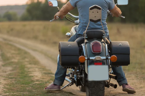 Jovem casal romântico em um campo em uma motocicleta — Fotografia de Stock