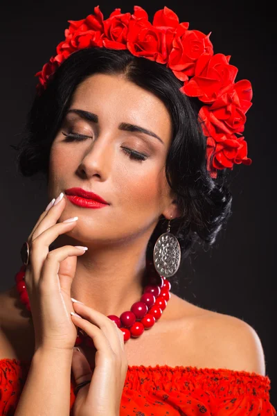 Belle femme sexy en rouge. Belle image de la fille en rouge. Couronne élégante de fleurs rouges, bijoux élégants, portrait d'une fille . — Photo