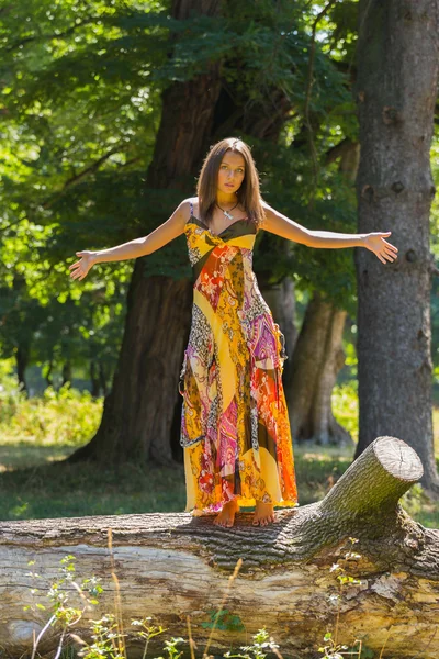 En ung och attraktiv flicka i vacker sommar klänning mitten av soliga ängar. Glad tjej Solar sig i varma strålar från sommarsolen. Vacker bild av en sorglös flicka. — Stockfoto