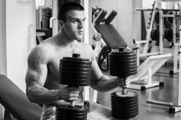 Vücut geliştirme dumbbells ile. Husky büyük bir dumbbell elinde tutar. Spor, vücut geliştirme, sağlıklı yaşam tarzı.