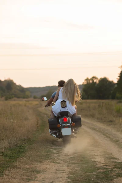 Recién casados en medio del campo en una carretera de motocicletas. Pareja feliz viajando en moto . — Foto de Stock