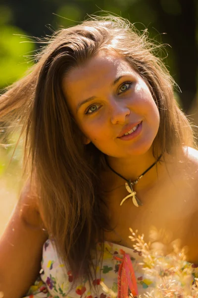 Una chica joven y atractiva en hermoso vestido de verano en medio de prados soleados. Chica alegre tomando el sol en los cálidos rayos del sol de verano. Hermosa imagen de una chica despreocupada . —  Fotos de Stock