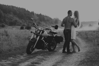 Siyah ve beyaz fotoğraf motorcu çift bir motosiklet alanında.