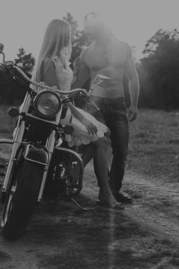 Siyah ve beyaz fotoğraf motorcu çift bir motosiklet alanında.