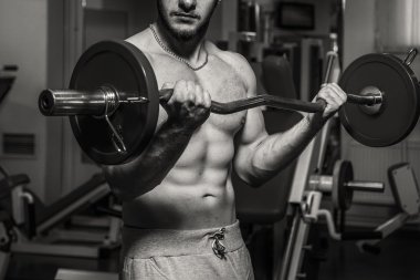 Kaslı adam spor salonunda ağırlık ile çalışma dışarı. Adam egzersizleri yapar.