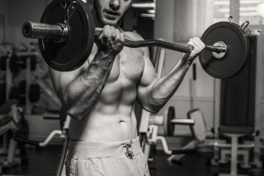 Kaslı adam spor salonunda ağırlık ile çalışma dışarı. Adam egzersizleri yapar.