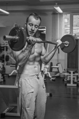 Kaslı adam spor salonunda ağırlık ile çalışma dışarı. Adam egzersizleri yapar.