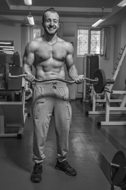 Kaslı adam spor salonunda ağırlık ile çalışma dışarı. Adam egzersizleri yapar.