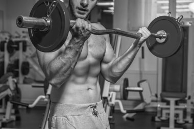 Kaslı adam spor salonunda ağırlık ile çalışma dışarı. Adam egzersizleri yapar.