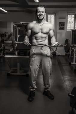 Kaslı adam spor salonunda ağırlık ile çalışma dışarı. Adam egzersizleri yapar.