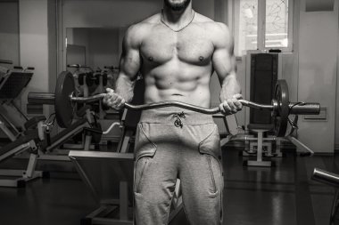 Kaslı adam spor salonunda ağırlık ile çalışma dışarı. Adam egzersizleri yapar.