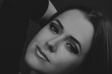 Karanlık bir arka plan üzerinde güzel, gizemli, şirin esmer. Siyah ve beyaz fotoğraf güzel gizemli esmer.