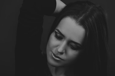 Karanlık bir arka plan üzerinde güzel, gizemli, şirin esmer. Siyah ve beyaz fotoğraf güzel gizemli esmer.