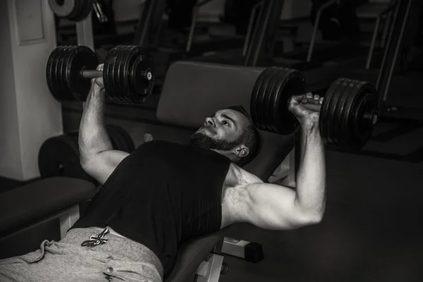 Hombre en el gimnasio. El hombre hace ejercicios de pesas. El deporte, el poder, las pesas, la tensión, el ejercicio - el concepto de un estilo de vida saludable. Artículo sobre fitness y deportes . —  Fotos de Stock