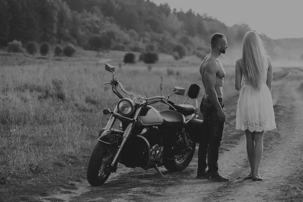 Blanco y negro foto motorista pareja en una motocicleta en el campo . —  Fotos de Stock