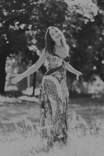 Foto menina bonita no parque. Um jovem vestido morena no meio de delicadas flores silvestres. Retrato foto em preto e branco de uma menina com maquiagem profissional . — Fotografia de Stock