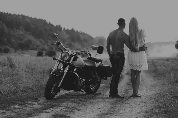 Blanco y negro foto motorista pareja en una motocicleta en el campo . —  Fotos de Stock