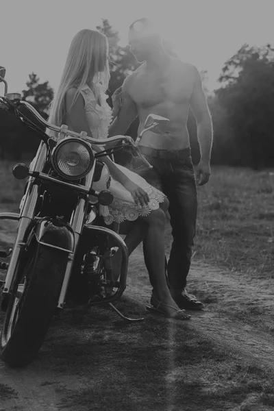 Siyah ve beyaz fotoğraf motorcu çift bir motosiklet alanında.