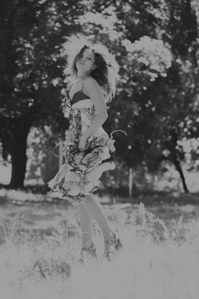 Foto menina bonita no parque. Um jovem vestido morena no meio de delicadas flores silvestres. Retrato foto em preto e branco de uma menina com maquiagem profissional . — Fotografia de Stock