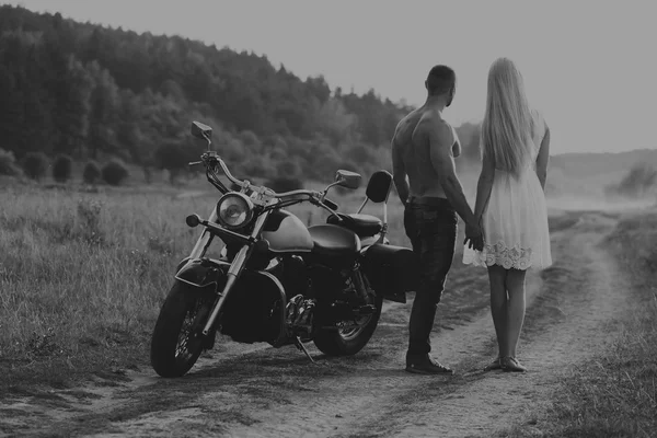 Černobílé fotografie motorkář pár na motorce v poli. — Stock fotografie