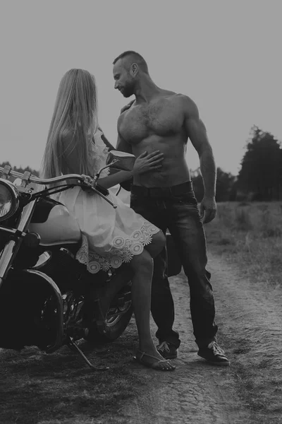 Preto e branco foto motociclista casal em uma motocicleta no campo . — Fotografia de Stock