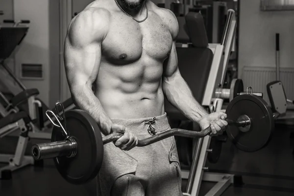 Lihaksikas mies treenaa painoja kuntosalilla. Ihminen tekee harjoituksia . — kuvapankkivalokuva