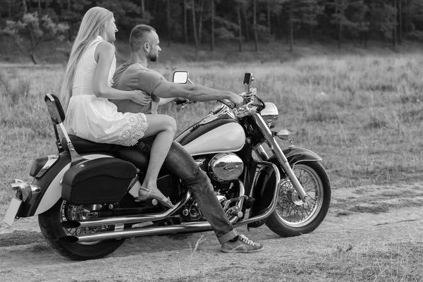 Nygifta mitten av fältet på en motorcykel road. Lyckliga par reser på en motorcykel. Extra liv. Svartvitt fotografi för sociala och affischer och webbplatser MC-tidningar. — Stockfoto