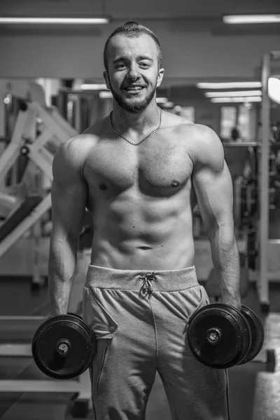 Man at the gym. Man makes exercises dumbbells. Sport, power, dumbbells, tension, exercise - the concept of a healthy lifestyle. Article about fitness and sports. — Stock Photo, Image