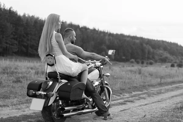 Frischvermählte mitten im Feld auf einer Motorradstraße. glückliches Paar, das auf einem Motorrad unterwegs ist. außergewöhnliches Leben. Schwarz-Weiß-Foto für soziale Medien, Plakate und Webseiten von Motorradzeitschriften. — Stockfoto