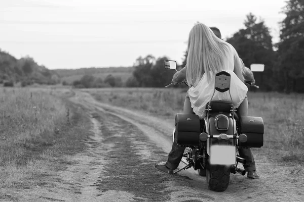 Frischvermählte mitten im Feld auf einer Motorradstraße. glückliches Paar, das auf einem Motorrad unterwegs ist. außergewöhnliches Leben. Schwarz-Weiß-Foto für soziale Medien, Plakate und Webseiten von Motorradzeitschriften. — Stockfoto