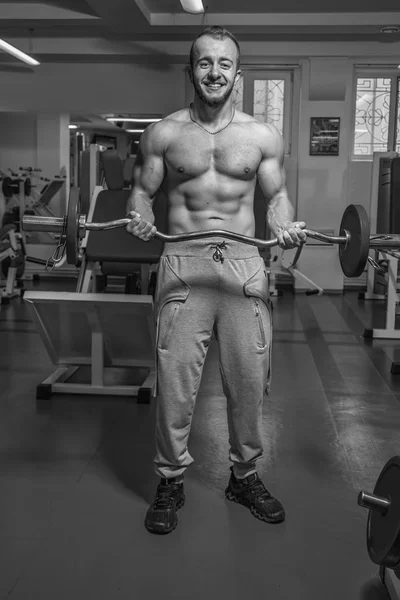 Gespierde man met gewichten in de sportschool uit te werken. Man maakt oefeningen. — Stockfoto