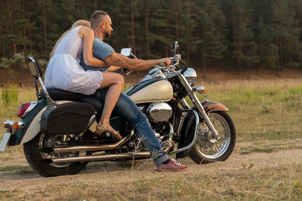 Young romantic couple in a field on a motorcycle — Stock Photo, Image