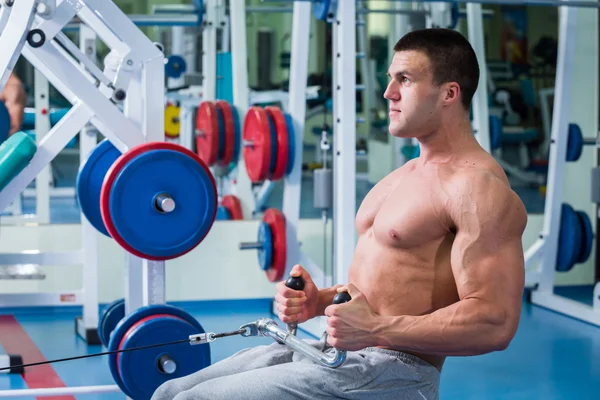 Forte uomo muscolare che fa esercizi in palestra . — Foto Stock