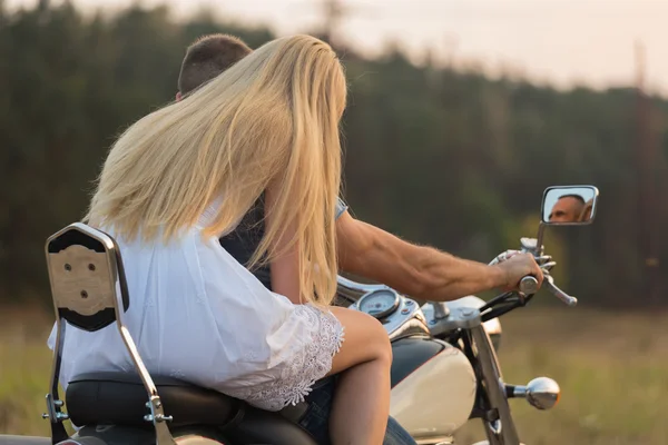 Joven pareja romántica en un campo en una motocicleta — Foto de Stock