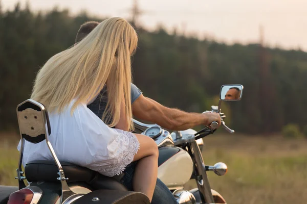 Young romantic couple in a field on a motorcycle — Stock Photo, Image