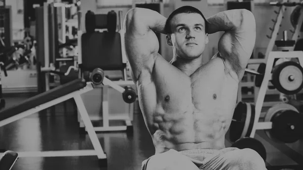 Сильный мускулистый человек делает упражнения в спортзале . — стоковое фото