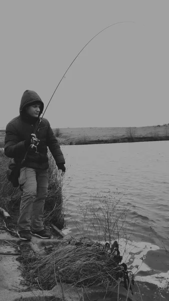 El pescador pesca en el invierno que gira. Pescador joven captura en el invierno, pesca deportiva, estilo de vida saludable, ocio, naturaleza . — Foto de Stock