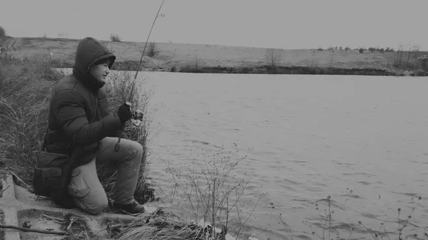 Pescador pesca em um inverno girando. Jovem pescador pega no inverno, pesca esportiva, estilo de vida saudável, lazer, natureza . — Fotografia de Stock