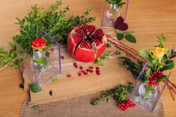 Hermosa composición con granada, flores y bulbos. Hermoso bodegón con una granada en el fondo de madera. Hermosa decoración de la composición de frutas y flores . —  Fotos de Stock