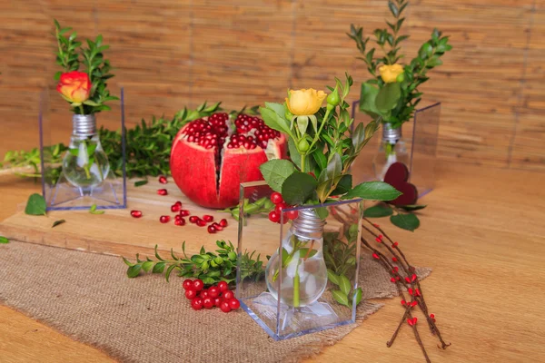 Hermosa composición con granada, flores y bulbos. Hermoso bodegón con una granada en el fondo de madera. Hermosa decoración de la composición de frutas y flores . —  Fotos de Stock