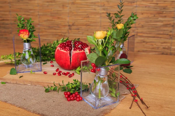 Hermosa composición con granada, flores y bulbos. Hermoso bodegón con una granada en el fondo de madera. Hermosa decoración de la composición de frutas y flores . —  Fotos de Stock