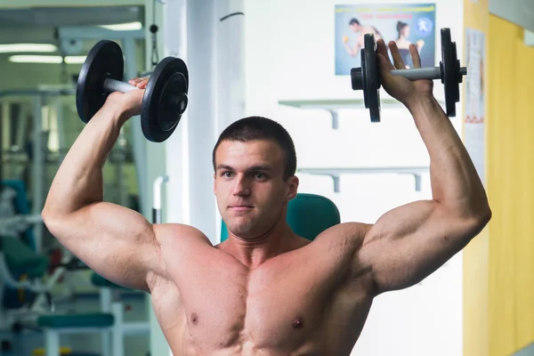 Hombre guapo, atlético y seguro en el gimnasio. postura culturismo — Foto de Stock