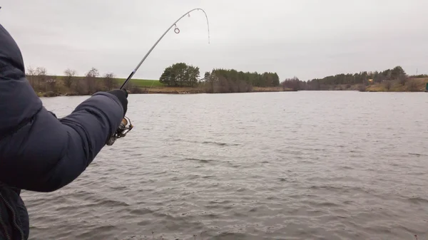 El pescador pesca en el invierno que gira. Pescador joven captura en el invierno, pesca deportiva, estilo de vida saludable, ocio, naturaleza . —  Fotos de Stock