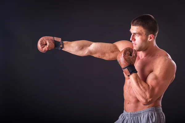 Silný boxer na černém pozadí. Svalnatý chlap v Boxerské rukavice. — Stock fotografie