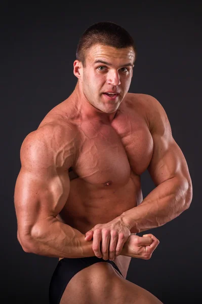 Professional bodybuilder shows his body on a dark background. Muscular body athlete. The result achieved by training and hard work on themselves. Photos for sporting magazines, posters and websites. — Stock Photo, Image