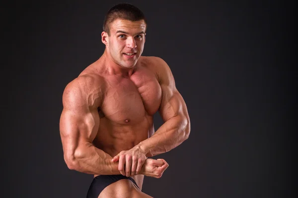 Fisiculturista profissional mostra seu corpo em um fundo escuro. Atleta do corpo muscular. O resultado alcançado pelo treinamento e trabalho duro sobre si mesmos. Fotos para revistas esportivas, cartazes e sites . — Fotografia de Stock