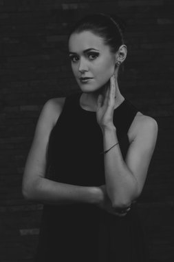 Karanlık bir arka plan üzerinde güzel, gizemli, şirin esmer. Siyah ve beyaz fotoğraf güzel gizemli esmer.