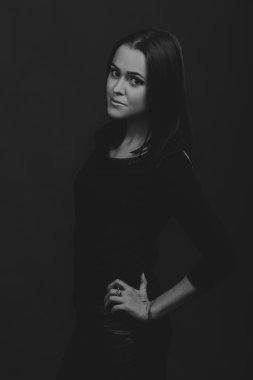 Karanlık bir arka plan üzerinde güzel, gizemli, şirin esmer. Siyah ve beyaz fotoğraf güzel gizemli esmer.